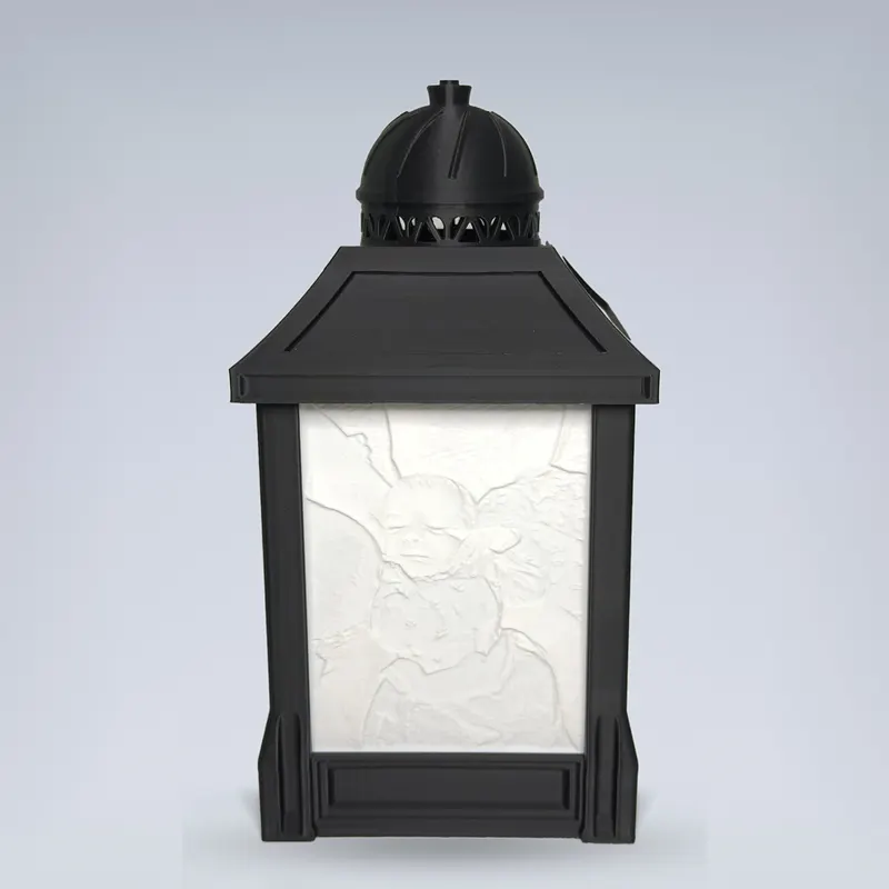 Custom lithophane photo lamp — black 3D printed lantern by day with sculpted photo relief panel, studio background